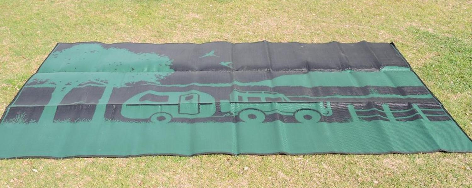 Off road camping mat for caravan set up available at Sunshine Coast Queensland at Jawa Off Road Camper Trailers. "Free camping" is a green and black mat with a design showing trees and a car pulling a caravan in the Australian outback.