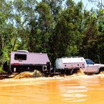 Jawa Solera 10 hybrid off road camper, small glamper for couples. Pictured towed by four wheel drive car through shallow and muddy waters through Australian bush.