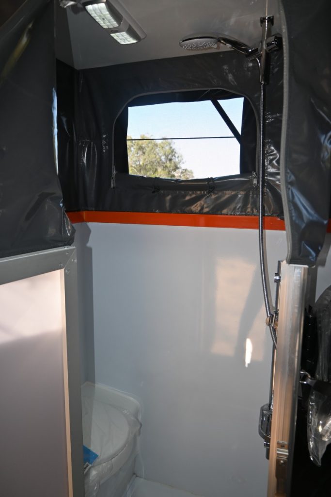 Jawa Lowdown 13 low hybrid off road camper for family of three made to fit standard garage, pictured inside through ensuite door showing shower on right and toilet on left.