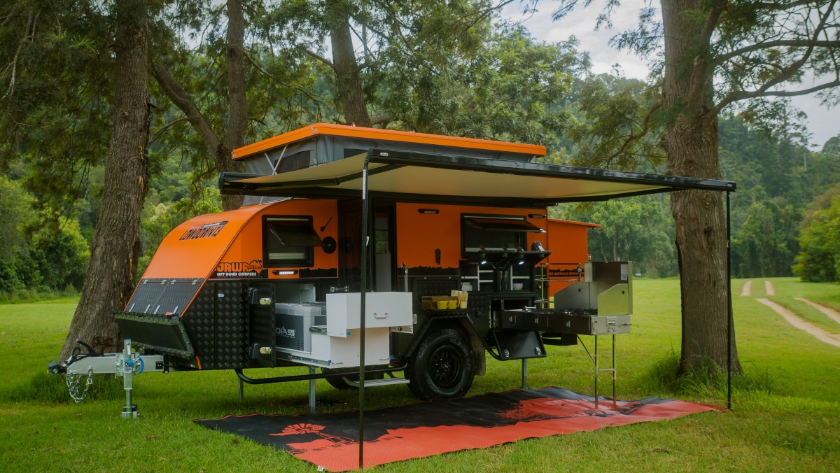 Jawa Lowdown 13 Camper Trailer set up in park reserve with alfresco kitchen and pantry set up over camping mat. Awning and roof popped out for comfortable campsite. Hybrid caravans stocked at Sunshine Coast Queensland.