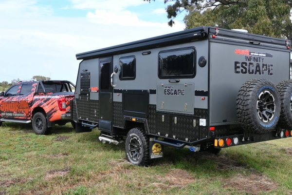 Infinity Escape Hybrid Caravan towed by a four wheel drive Ute over grass. Camper trailer towed at 15 feet and roof down for compact travel. Large Jawa Off Road Camper for purchase at Sunshine Coast Queensland.
