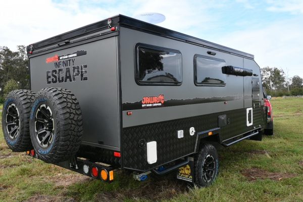 Back view of Jawa Infinity Escape off road towed by four wheel drive Ute. View of spare dual wheels and logo on back of very large family hybrid caravan - on sale at Sunshine Coast Queensland.