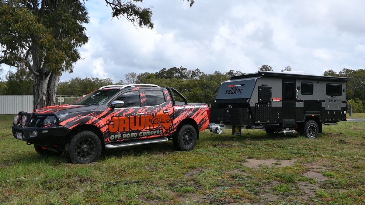 Jawa Infinity Escape hybrid off road camper trailer, large and spacious camper for couples, pictured in grassy area towed by four wheel drive ute covered in Jawa branding.