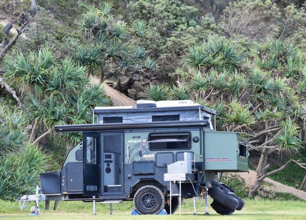 Tough Jawa Stealth 12 Hybrid Caravan parked on a bushland reserve. Green design with plenty of features built for off roading adventures. For sale in Sunshine Coast Queensland.