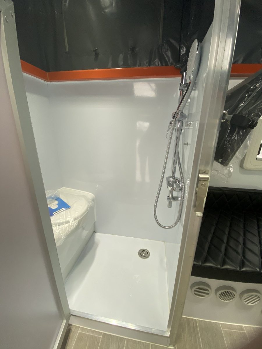 Jawa Lowdown 13 Cupboard low hybrid poptop off road camper with lots of storage perfect for adventuring couples and storing in standard garage, pictured inside through ensuite doorway showing shower on right wall and toilet on left wall, ensuite made with glossy fibreglass.