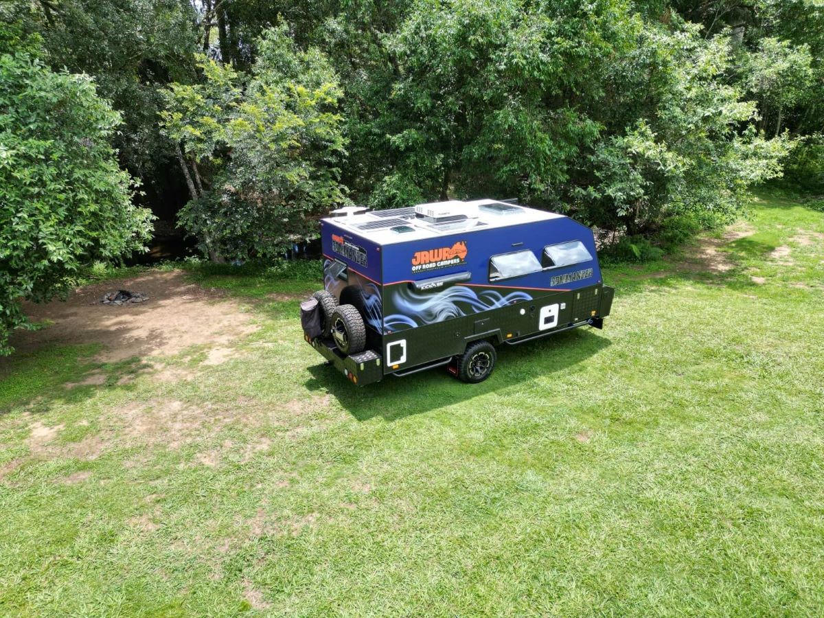 Jawa Commander hardtop off road camper perfect for luxury and adventure, pictured in a green camping reserve with trees in the background wide view.