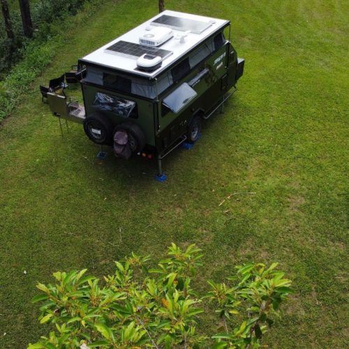 Jawa Stealth 15 hybrid off road camper with solid back for easy camping, pictured at green bush campsite with a drone from above, poptop roof extended.
