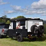 Jawa Stealth 10 hybrid compact off road camper trailer, small size camper for couples, pictured on grassy and hilly landscape towed by four wheel drive.