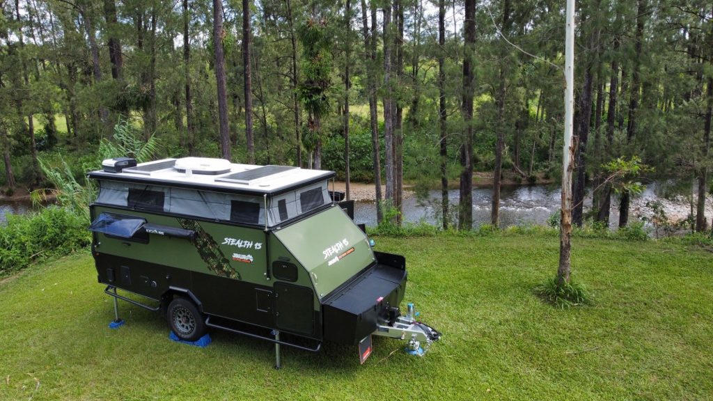 JAWA Stealth off road camper parked in wooded area next to rapidly running river